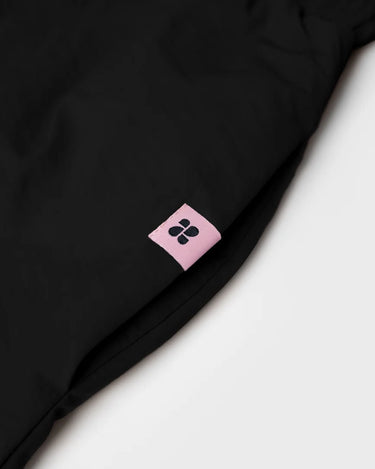 Black vegan skirt made from recycled materials with a pink logo tag. - The New Orchard CH