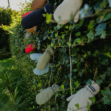 Vegan winter gloves in cinnamon brown and cream, made from recycled materials, hanging outdoors. - The New Orchard CH