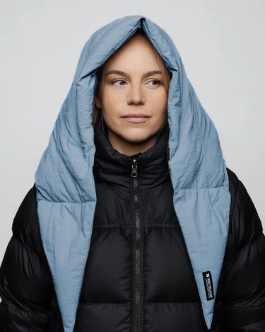Sky blue vegan puffer winter capuche made from recycled materials, worn over black jacket. - The New Orchard CH