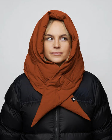 Woman wearing cinnamon-colored vegan hood made from recycled materials over black puffer jacket. - The New Orchard CH