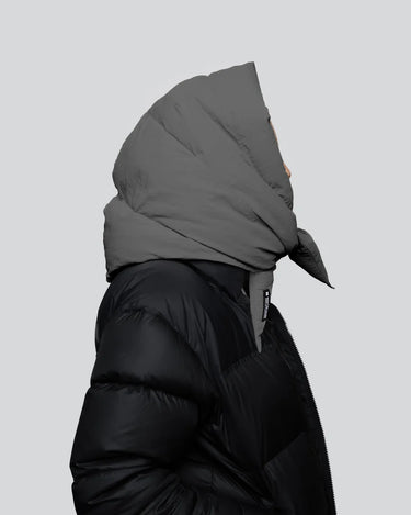 Black vegan puffer jacket with recycled materials and oversized grey hood covering head. - The New Orchard CH