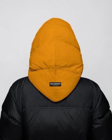 Amber yellow vegan winter capuche made from recycled materials, shown on black puffer jacket back. - The New Orchard CH