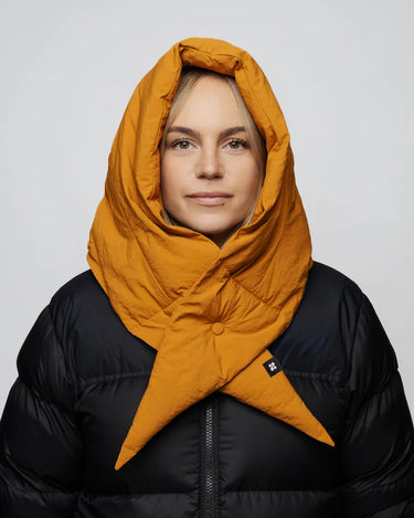 Amber yellow vegan winter capuche made from recycled materials, styled over black puffer jacket. - The New Orchard CH