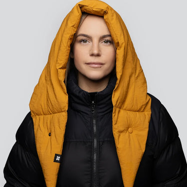 Amber yellow vegan winter capuche made from recycled materials worn over black puffer jacket. - The New Orchard CH
