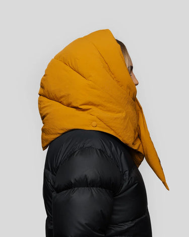 Amber yellow vegan puffer hood made from recycled materials, worn with black jacket. - The New Orchard CH