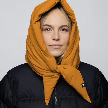 Amber yellow vegan capuche hood made from recycled materials, styled over a black puffer jacket. - The New Orchard CH