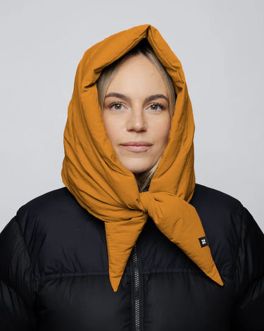 Amber yellow vegan capuche hood made from recycled materials, styled over a black puffer jacket. - The New Orchard CH