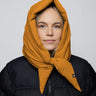 Amber yellow vegan capuche hood made from recycled materials, styled over a black puffer jacket. - The New Orchard CH