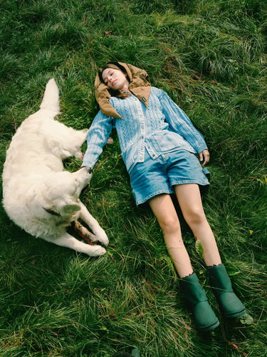 Person lying on grass with a white dog