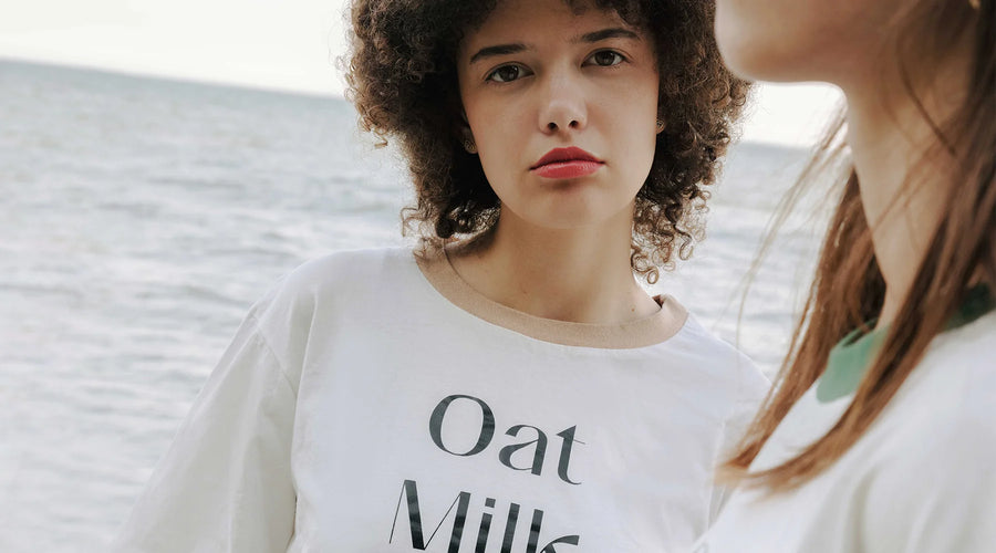 Woman wearing a white t-shirt with 'Oat Milk' text on a beach