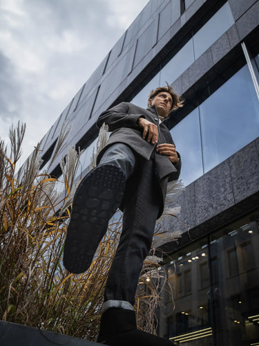Person in a suit standing on a ledge with a modern building in the background