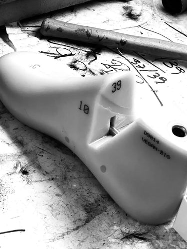 White plastic component with markings on a dirty workbench