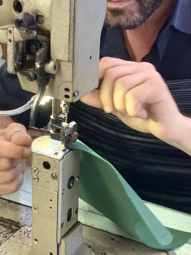 Person using a sewing machine to work on a green fabric item.