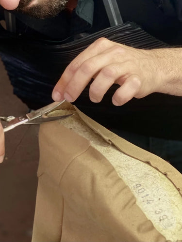 Person cutting a beige shoe with scissors, focusing on the action.