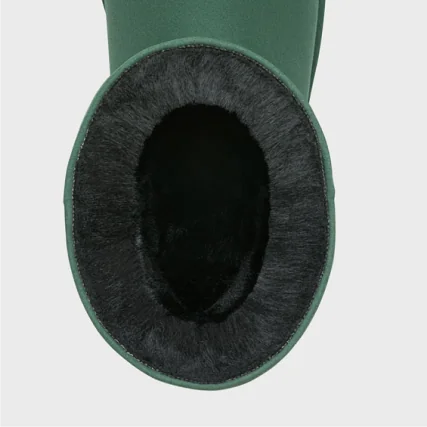 Close-up of a green boot with black vegan fur lining on a light gray background